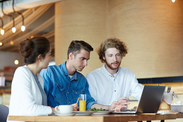 Canvas Print - Group of students preparing coursework or joint project in front of laptop