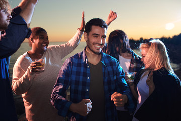 Poster - Ecstatic guys and girls dancing in the dusk on the beach