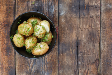 Wall Mural - Boiled young potatoes with dill and butter on a wooden table, top view, closeup. rustic style