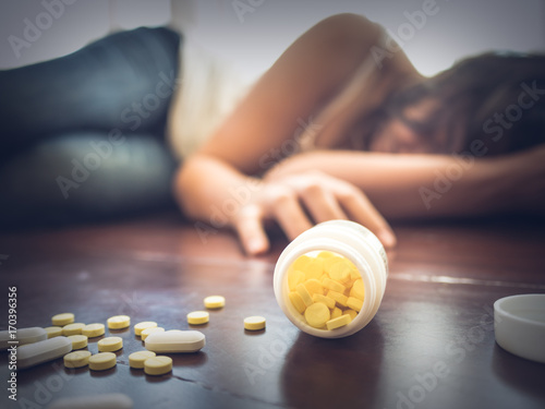 Cuadros en Lienzo Woman taking medicine overdose and lying on the wooden floor with open pills bottle