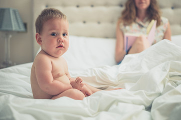 Wall Mural - Mother in bed with baby reading from diary