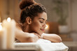 © Cookie Studio - Beautiful african girl resting relaxing in spa resort with closed eyes.