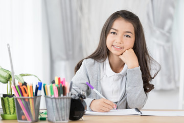 cute asia girl writing something in paper with colour pencils