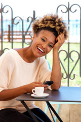 Wall Mural - African woman with mobile phone in coffee shop