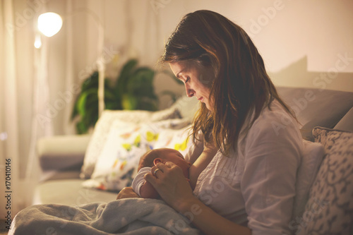 Fotografía Young beautiful mother, breastfeeding her newborn baby boy at night