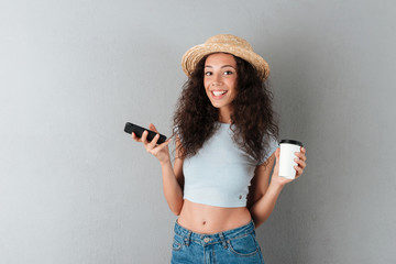 Sticker - Happy curly woman in hat with smartphone and coffee