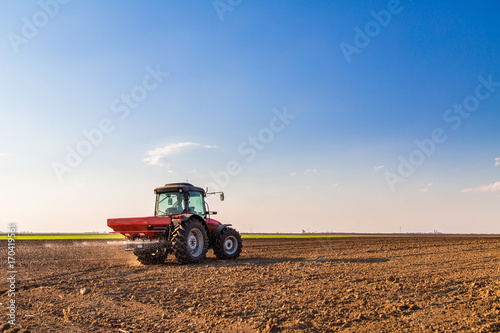 Fényképezés Farmer fertilizing arable land with nitrogen, phosphorus, potassium fertilizer