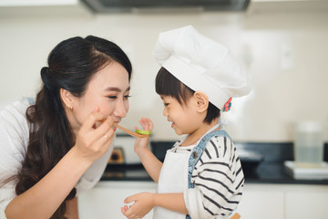 Wall Mural - Happy family in the kitchen. Mother and child daughter are preparing the vegetables and fruit.