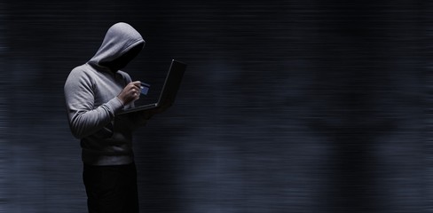 Poster - composite image of hacker using laptop while holding credit card