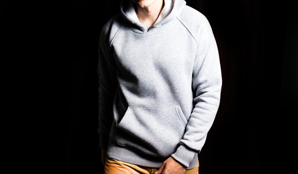 Fototapete - man  in the blank grey hoodie, sweatshirt on a black background, mock up, free space