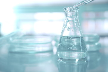 Wall Mural - pipette drop water in flask with blur petri dish in medical science laboratory background