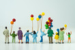 back view of miniature happy family holding balloons with white background as happy family concept.