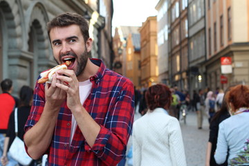 Joyful man eating fast food on the street 