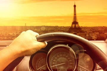 View on the dashboard of the truck driving.The driver is holding the steering wheel. Eiffel tower is in front of the car.