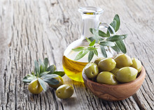 Virgin Olive Oil And Green Olives On Wooden Board