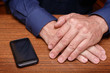 © rs31 - The hands of an adult man on the desk next to the mobile phone