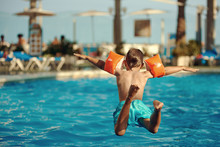 Caucasian Boy Having Fun Jumping Into The Pool.