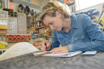 female architect working on blueprint at table in workshop