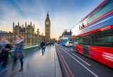 Fototapeta  - London, England - The iconic Big Ben and the Houses of Parliament with famous red double-decker bus and tourists on the move on Westminster bridge at sunset