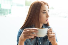 Thoughtful Woman Holding Coffee Cup By Window