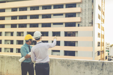 smiling young architect or engineering builder in hard hat with tablet over group of builders at construction site, architect watching some a construction, business, building, industry, people concept