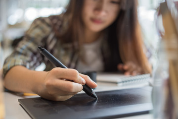 Leinwandbilder - Young female designer using graphics tablet while working with computer at studio or office.