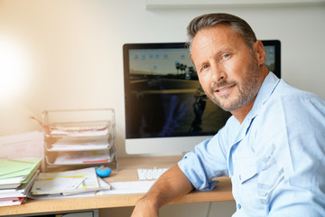 Wall Mural - Cheerful mature man sitting in home-office