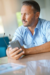 Wall Mural - Mature man being thoughtful looking at message on smartphone