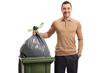 Young man throwing out the garbage and smiling