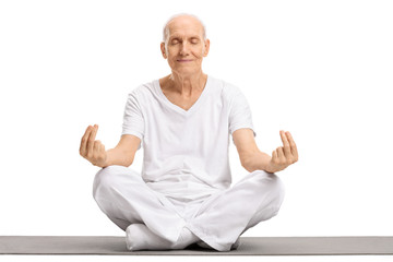 Canvas Print - Elderly man meditating on an exercise mat