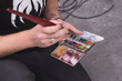 © Gonzales Photo - Artist is dipping his brush in a watercolour painting sets
