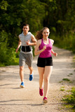 Fototapeta Las - Active young couple running in the park