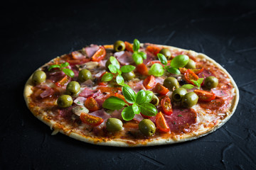 Pizza on a thin dough with olives and fresh basil