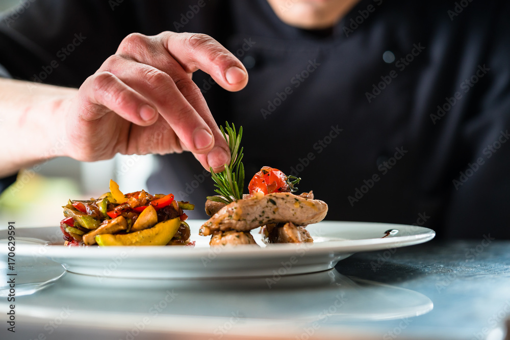 Chef finishing and garnishing food he prepared, a dish with pork meat and vegetables - obrazy, fototapety, plakaty 