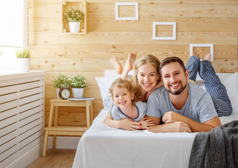 Wall Mural - happy family mother, father and child   laughs in bed