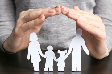 Poster - Woman covering paper silhouette of family with hands, closeup. Insurance concept