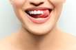 © Africa Studio - Young smiling woman licking her teeth on light background, closeup