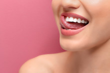 Young Smiling Woman Licking Her Teeth On Colour Background, Closeup