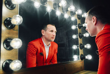 Fashion Man In Red Suit Looks In Mirror.