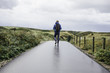 © Ivo de Bruijn/Stocksy - Young man with a backpack walking on a wet road in the middle of