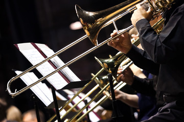 Trombones in the hands of musicians in the orchestra closeup