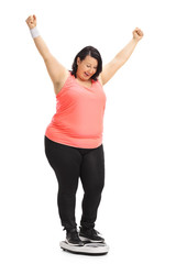 Wall Mural - Overweight woman on a weight scale gesturing happiness