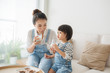 © makistock - Adorable girl eating cookies and drinking milk with her mother.