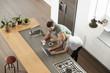 © Monkey Business - Overhead View Of Couple Looking At Laptop In Modern Kitchen
