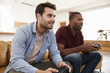© Monkey Business - Two Male Friends Sitting On Sofa In Lounge Playing Video Game
