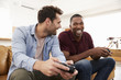 © Monkey Business - Two Male Friends Sitting On Sofa In Lounge Playing Video Game