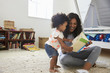 © Monkey Business - Mother And Baby Daughter Reading Book In Playroom Together