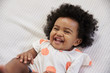 © Monkey Business - Parent Tickling Laughing Baby Girl Lying On Bed