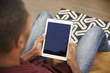 © Monkey Business - Man Sitting On Sofa At Home Looking At Digital Tablet