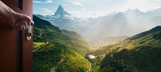 hand opens empty room door to nature and mountains